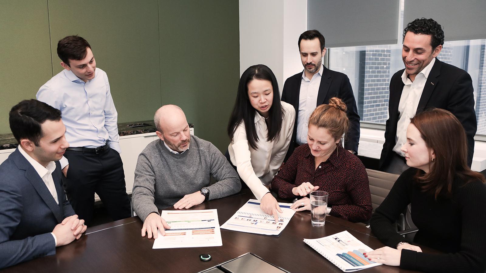 group of individuals looking at documents on a table